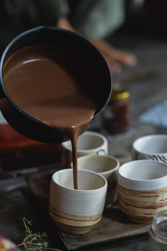 Ceremonial cacao being poured into handmade ceramic cups